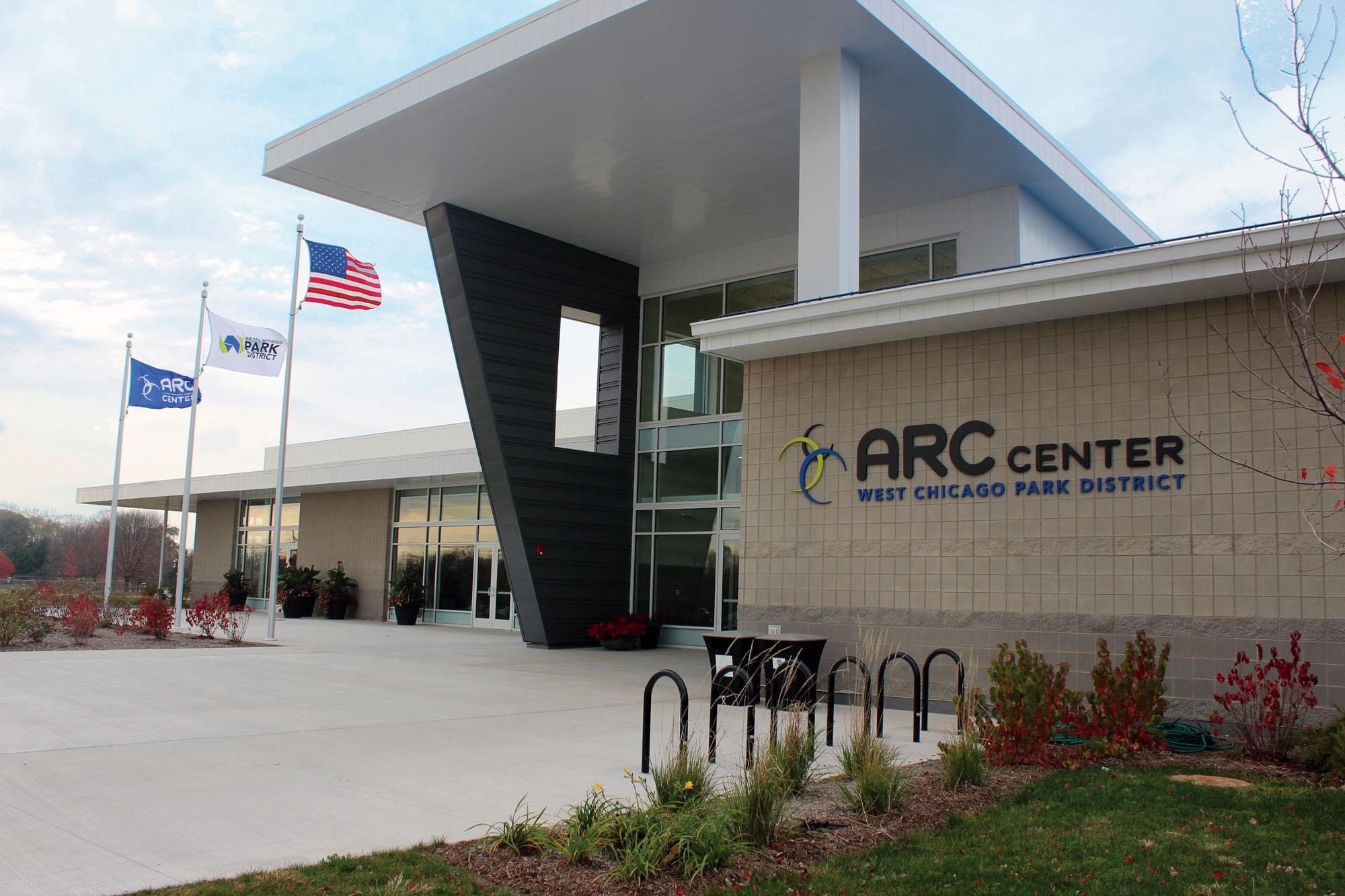 Photo of the front of the ARC Center building. Three flags fly in front of the building, the US flag, the park district flag and the ARC center flag.