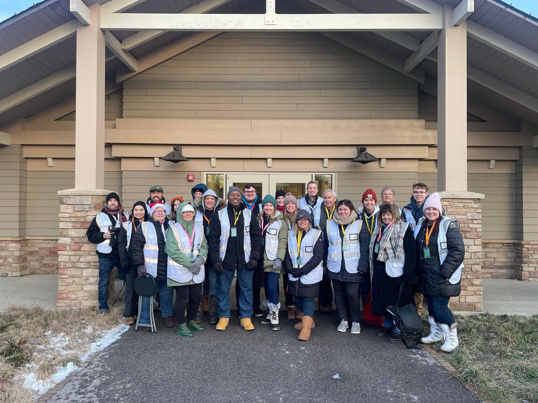 A group of volunteers are standing in front of a building at Cantigny Park on a cold day. They appear happy and ready to work.