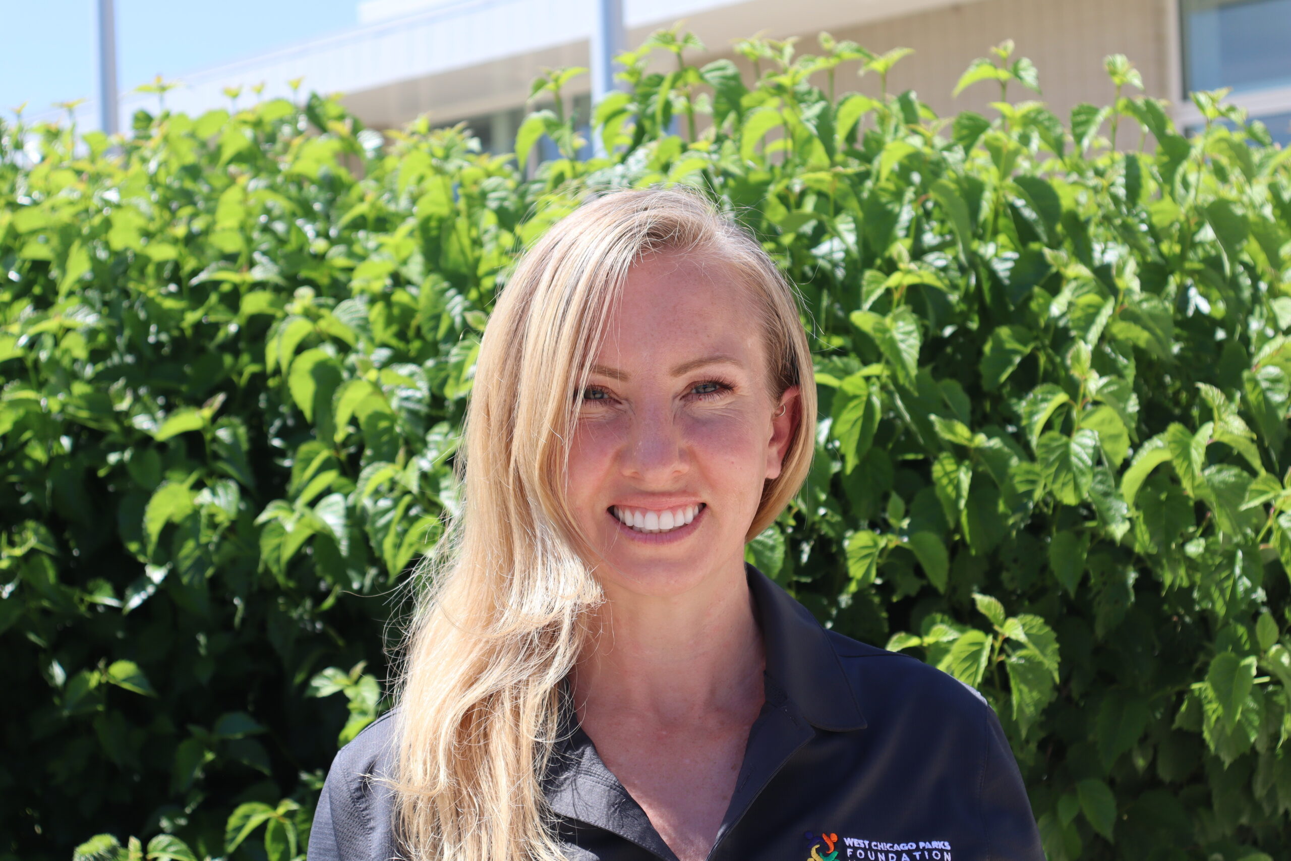 A headshot of Rebecca Holmes, board secretary, wearing a Foundation polo shirt. She is smiling and sitting outside. 