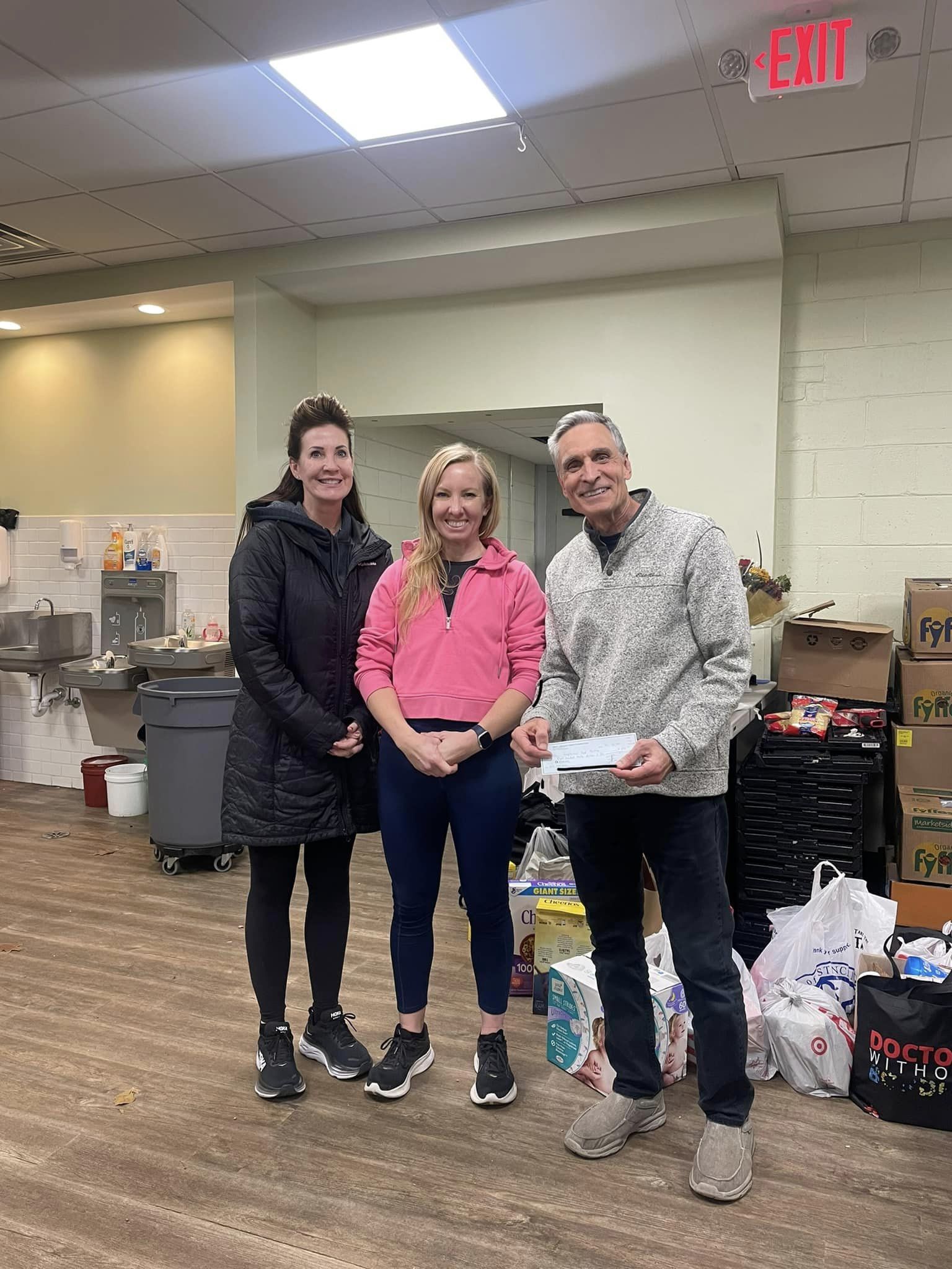 Two Foundation board members are presenting a man with a check donation to the West Chicago Neighborhood Food Pantry