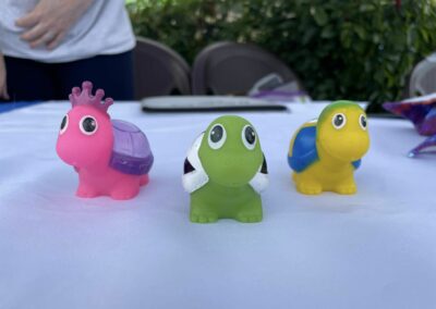 Three small, colorful, rubber turtles are posed with one turtle in front, and two turtles slightly behind.